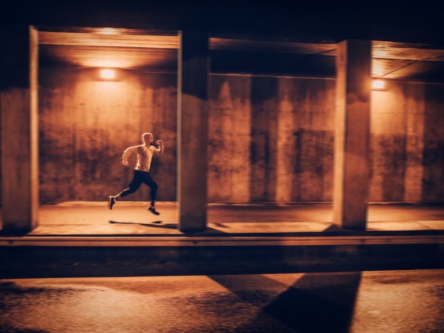 fotografia de homem correndo a noite em um local com pouca iluminação. 