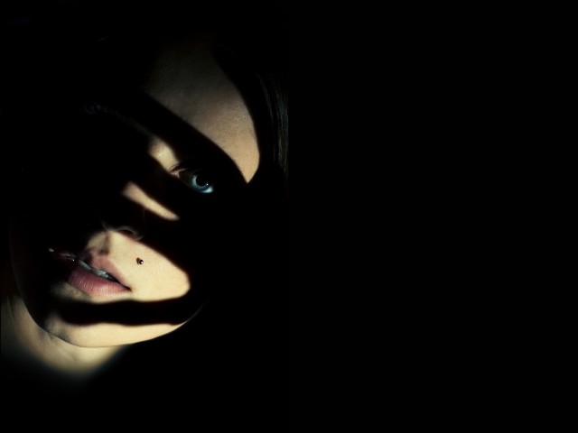 fotografia de rosto de uma mulher no escuro cobercom sombra