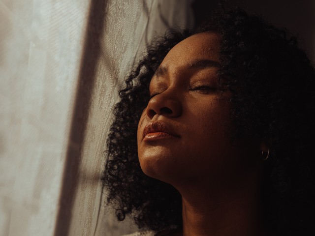 foto de uma mulher perto da janela com cortinas. Nessa caprtura foram aplicados efeitos para fotos