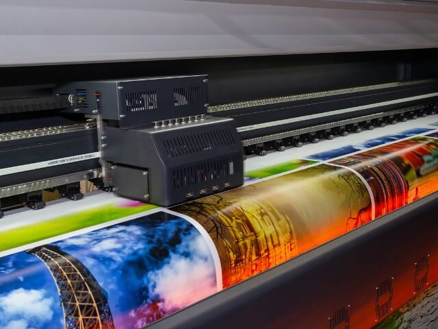 Impressora imprimindo em papel brilante diversas fotografias de paisagem e em cores.