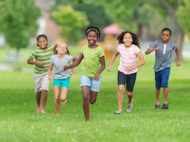 Crianças correndo em um gramado verde durante um ensaio fotográfico infantil