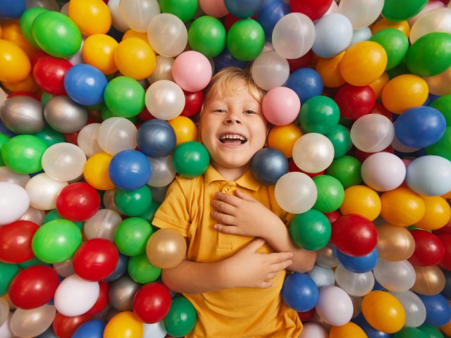 criança sorrindo em uma piscina de bolinhas coloridas