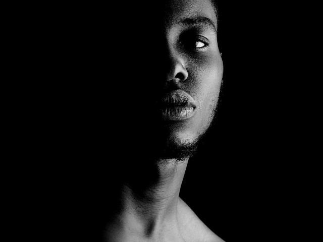Linda fotografia do rosto de um homem efeito chiaroscuro em preto e branco