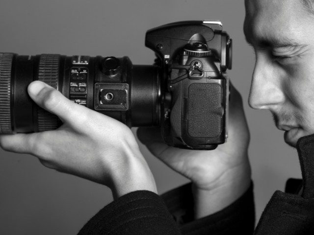 Fotografia em preto e branco de um homem com camera fotografica. 