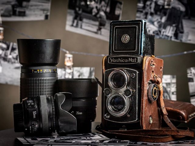 Iagem de lentes de cãmeras modernas, mas ao lado uma bem antiga mostrando a evolução das cameras fotográficas após a criação da primeira câmera. 