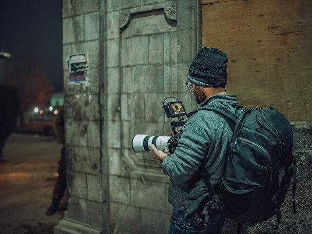 Fotógrafo trabalhando com fotojornalismo na rua a noite